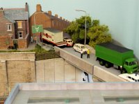 UP DKM-18  A road overbridge disguises the mainline exit to the fiddle-yard/cassette. The local constabulary have stopped the traffic, as they investigate an incident involving a green lorry
